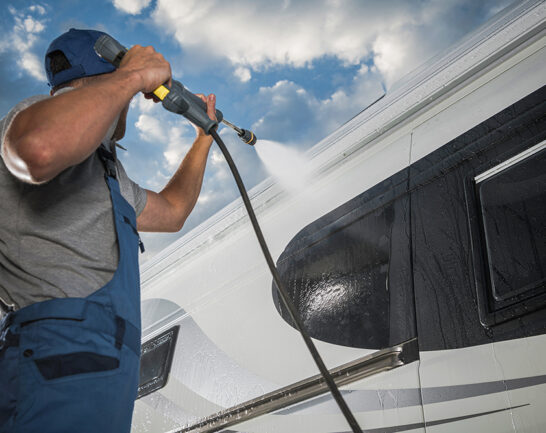 Man spuit camper schoon met hogedrukreiniger.