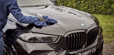 BMW X5 wordt gepoetst met een waxdoek.
